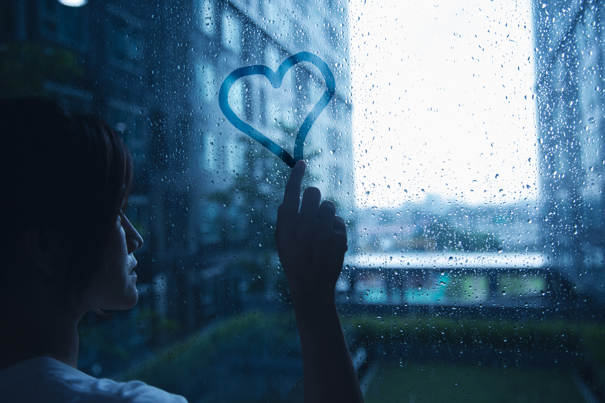 Woman drawing a heart on a window representing someone who is suffering from person addiction